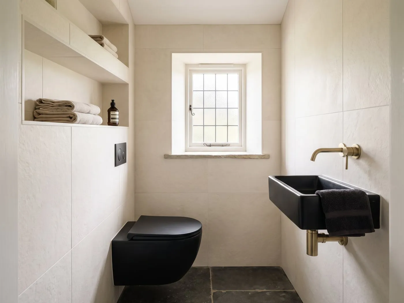 The same cloakroom after the work, with a wall-hung basin and new tiling