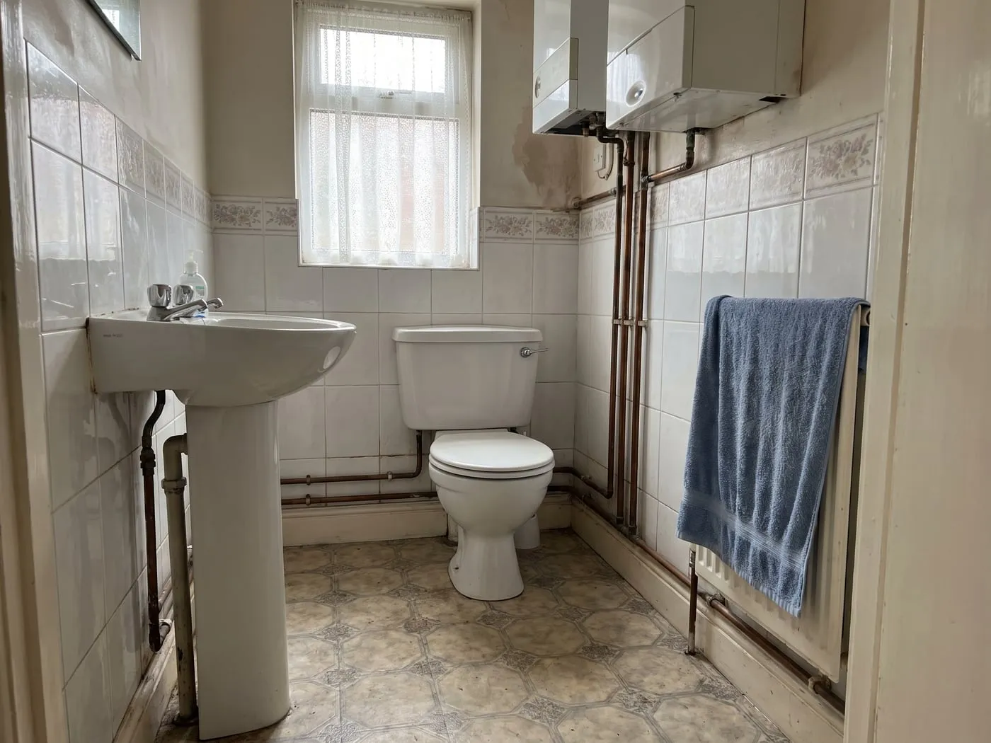 Cloakroom before the work, with dated tiling and a pedestal basin