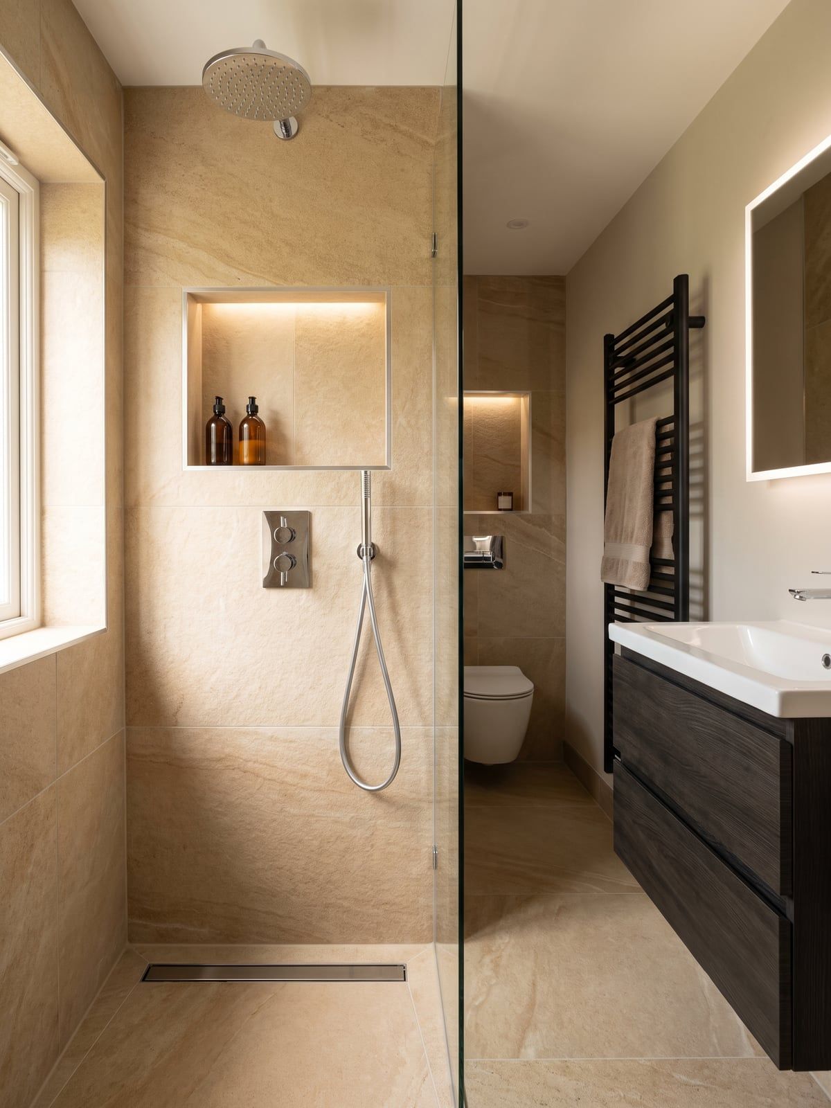 Shower in warm sandstone-effect tile with a deep lit recess and a chrome shower set