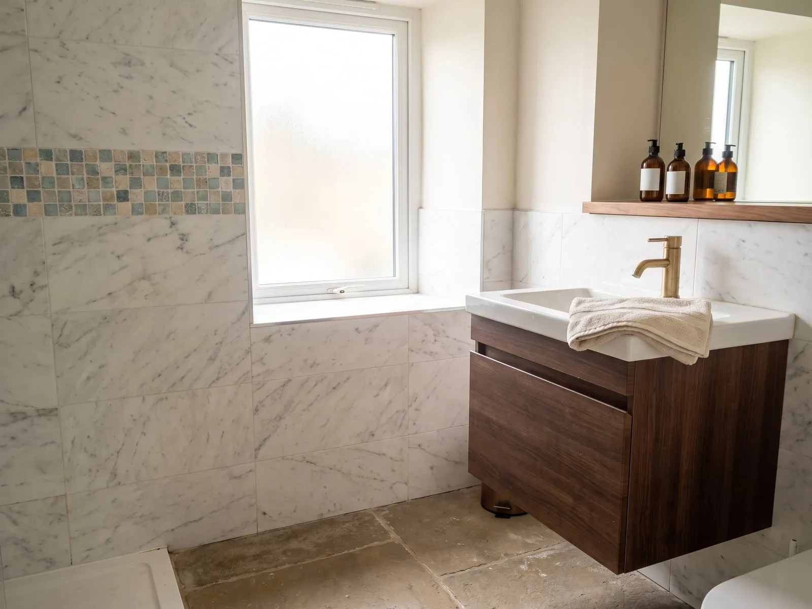 Marble-effect wall with a mosaic band above a wall-hung basin