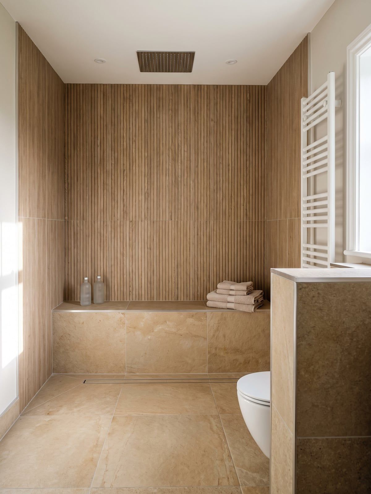 Shower area with fluted oak-effect wall panels, a tiled built-in bench and a linear drain in the floor